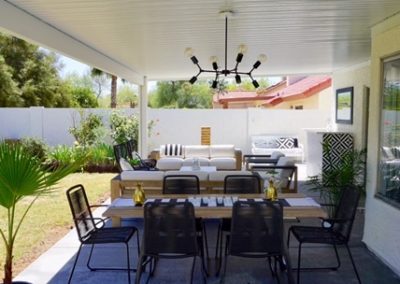 A photograph of a solid Alumawood patio cover installation extending from a home, showing how it creates a fully shaded and protected outdoor living area.