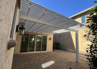 A photograph of a completed patio cover installation, showcasing the structure's clean design and the comfortable shade it provides for an outdoor residential living area.
