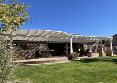 A photograph of a completed patio cover installation, showcasing the structure's clean design and the comfortable shade it provides for an outdoor residential living area.